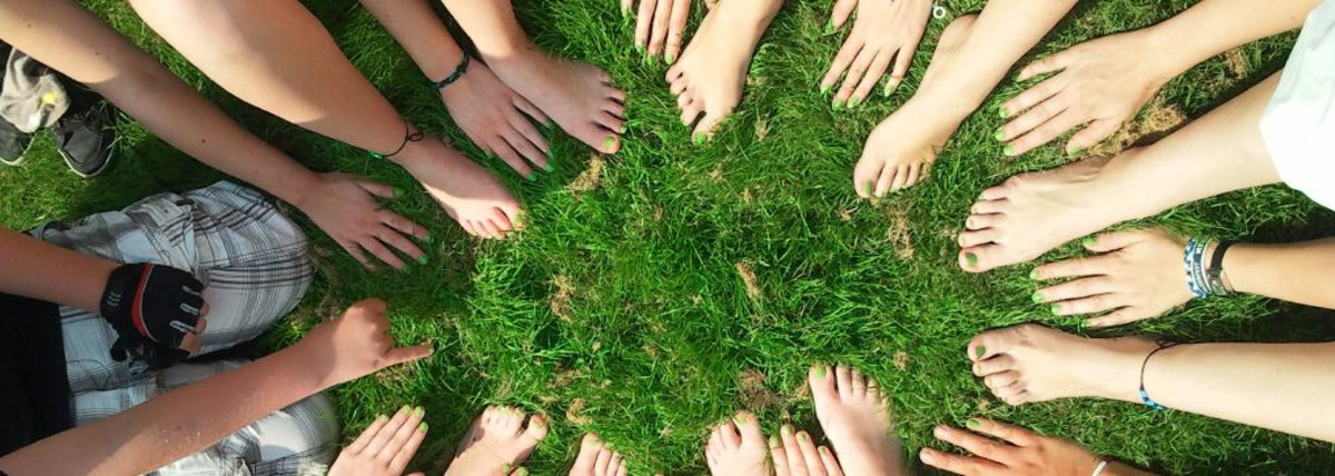 Zu sehen sind auf grünem Gras Hände und Füße, die einen Stern bilden.
