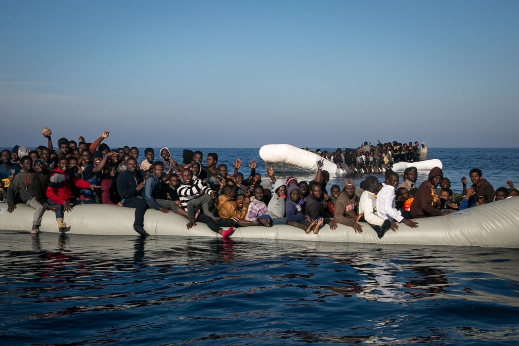 Zwei überfüllte Schlauchbote im Meer, in denen Geflüchtete Menschen sitzen. Beide am sinken.