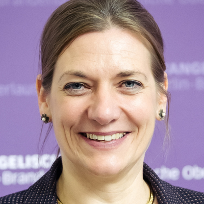 Portrait der Konsistorialpräsidentin Dr. Viola Vogel vor violettem Hintergrund, auf dem das EKBO Zeichen zu sehen ist.