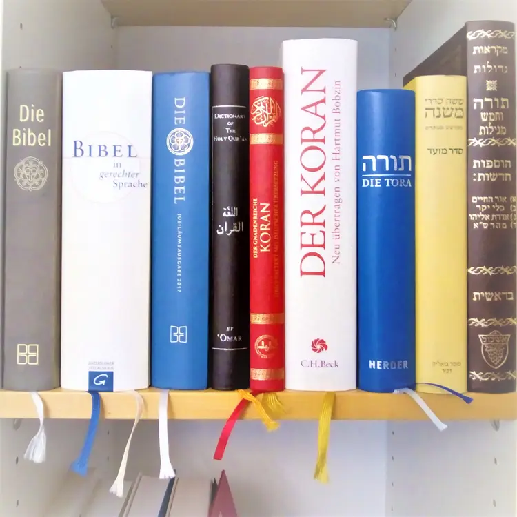 Die heiligen Bücher verschiedener Religionen in einem Regal.