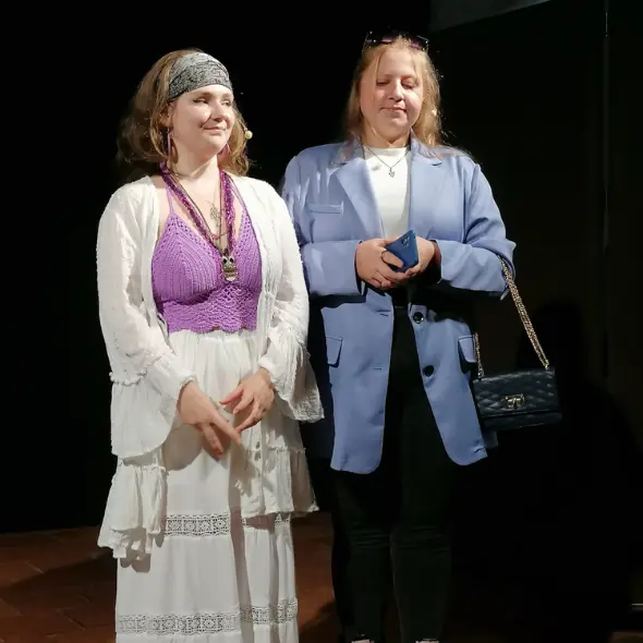 Zwei junge Frauen stehen hell beleuchtet auf einer Bühne und spielen ein Theaterstück im Rahmen des Jugendtheaters.