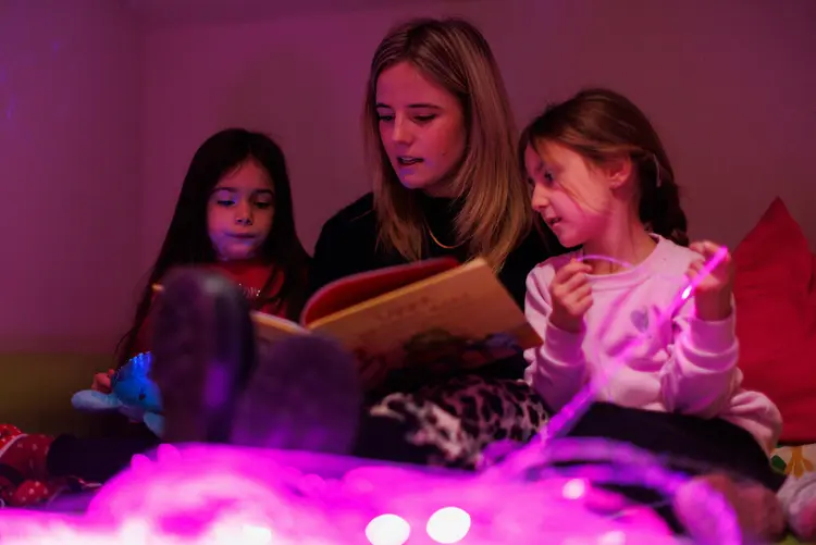 Eine Frau liest zwei Kindern aus einem Buch vor.