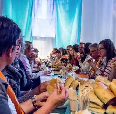 Mehrere Personen sitzen an einem Tisch und essen Brot.