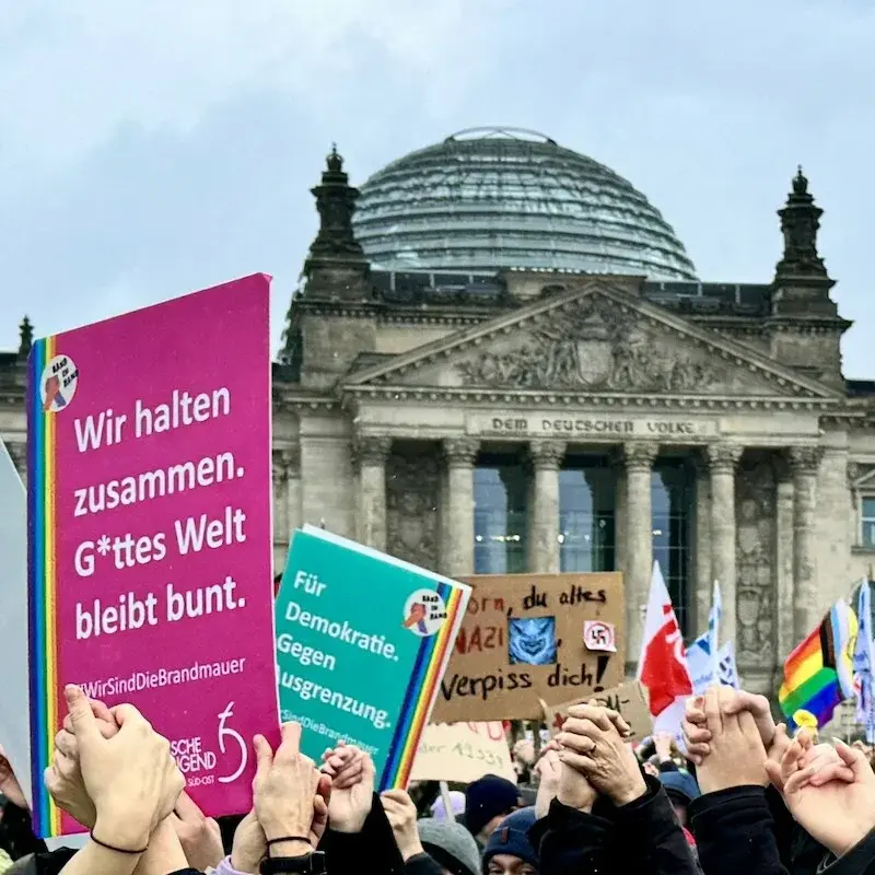 Menschen, die sich vor dem Reichstag zum Protestieren versammelt haben und Plakate für den Schutz der Demokratie in die Luft halten.