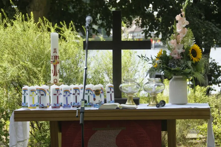 Ein festlich geschmückter Altar voller Taufkerzen bei einem Openair-Tauffest.