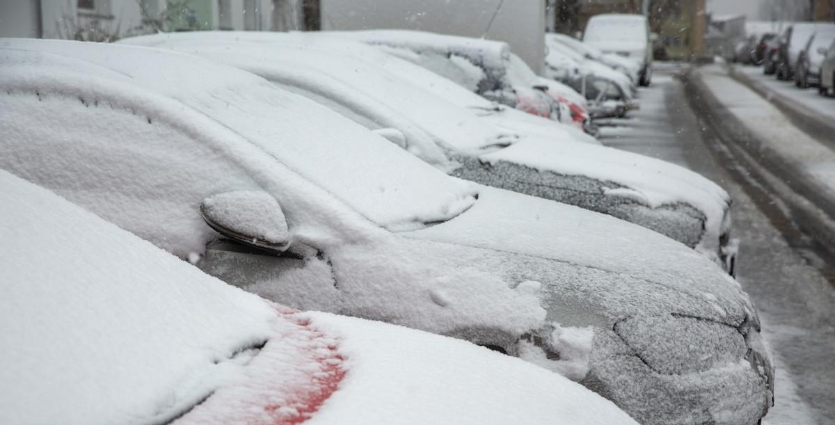 Schneebedeckte Autos parken am Straßenrand