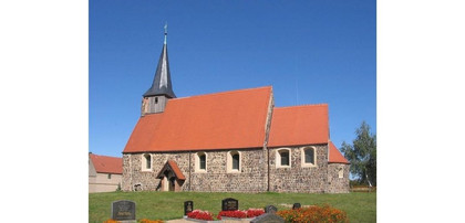 Mittelalterliche Dorfkirche aus Feldsteinen unter blauem Himmel (Südansicht)