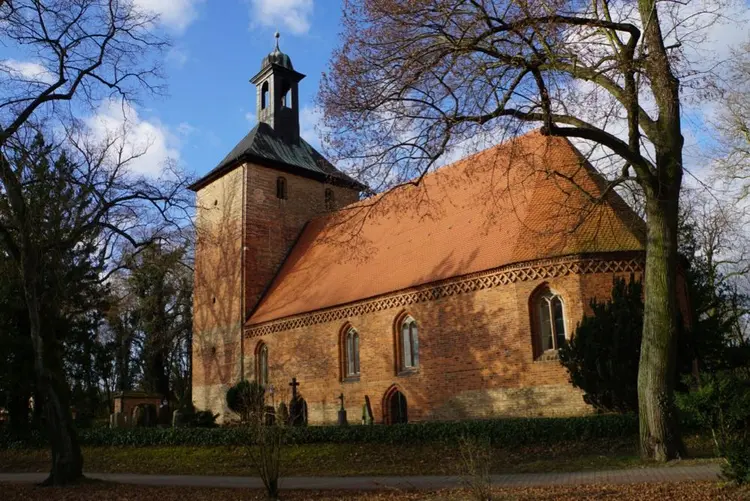 Das Gebäude der Dorfkirche Kleinmachnow vor blauem Himmel.