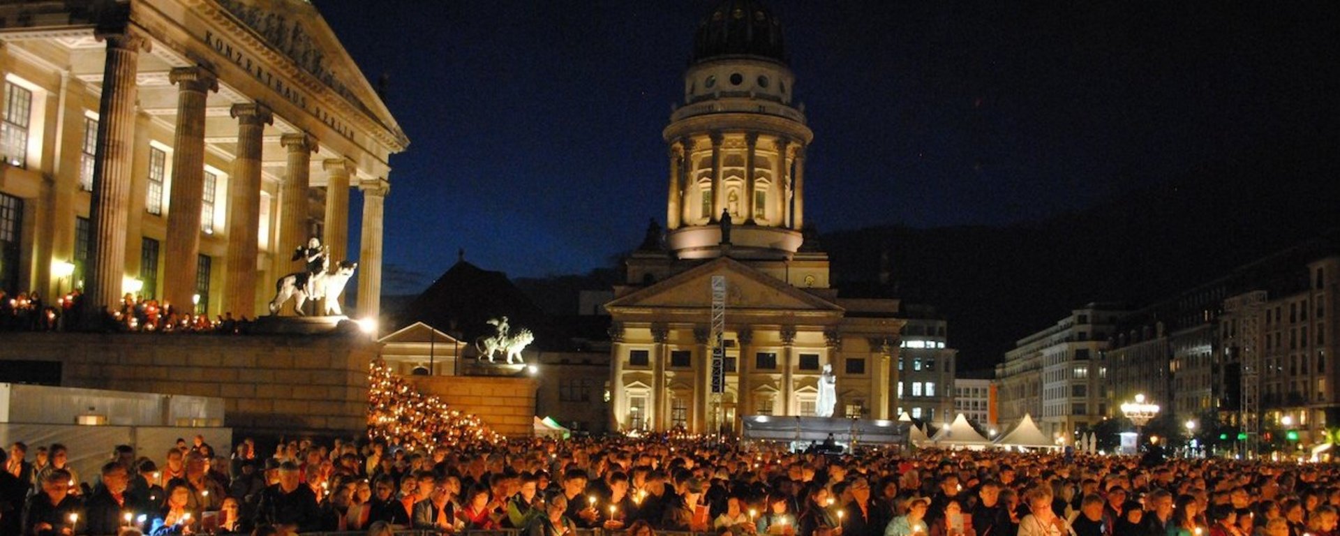 Menschen, die sich am Kirchentag zum Abendsegen versammeln und Lichter in der Hand halten.