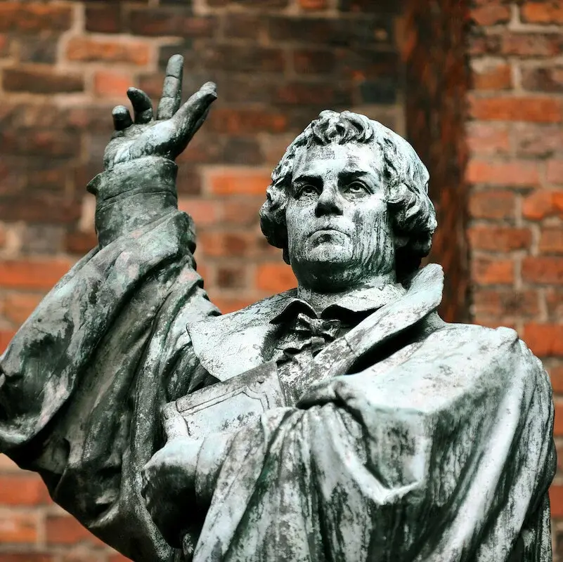 Statue von Martin Luther vor einer Kirche.