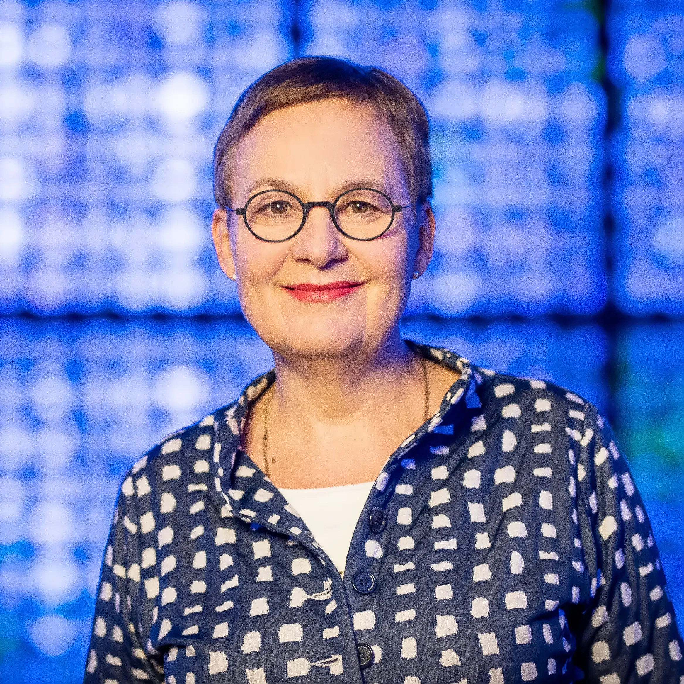 Portrait von Ulrike Trautwein vor blauem Hintergrund.