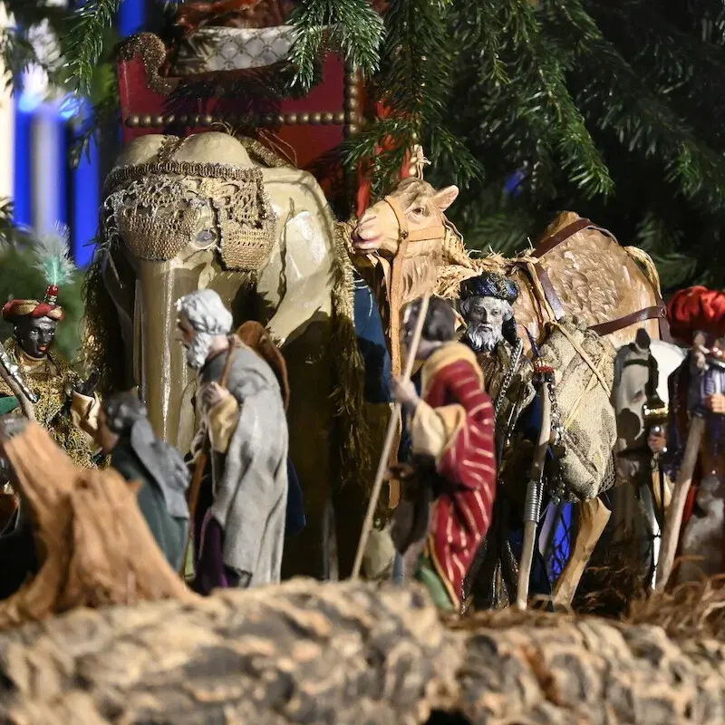 Kleine Figuren in Gewändern mit Wanderstöcken und Kamel, Elefant und Pferd.