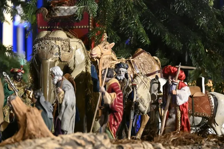 Kleine Figuren in Gewändern mit Wanderstöcken und Kamel, Elefant und Pferd.