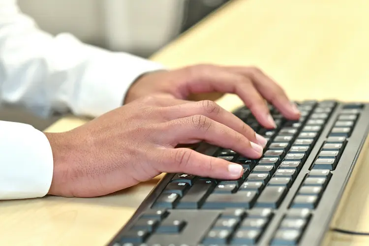 Zwei Hände, die auf einer Tastatur tippen.