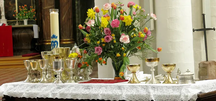 Ein gedeckter Tisch mit Blumen und Kelchen für das Abendmahl.