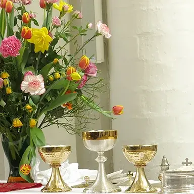 Ein gedeckter Tisch mit Blumen und Kelchen für das Abendmahl.