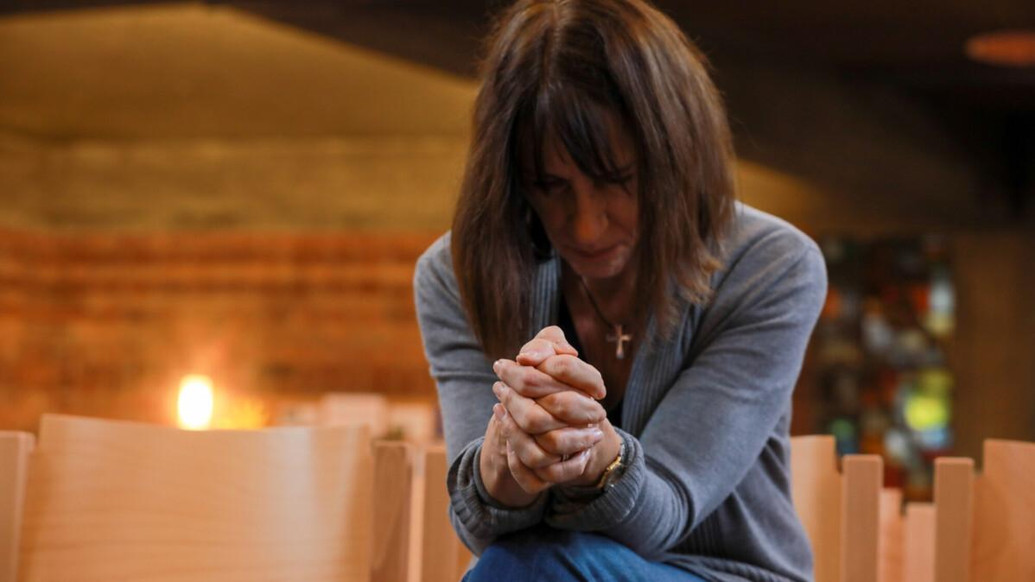Frau mit gefalteten Händen versunken in ein Gebet
