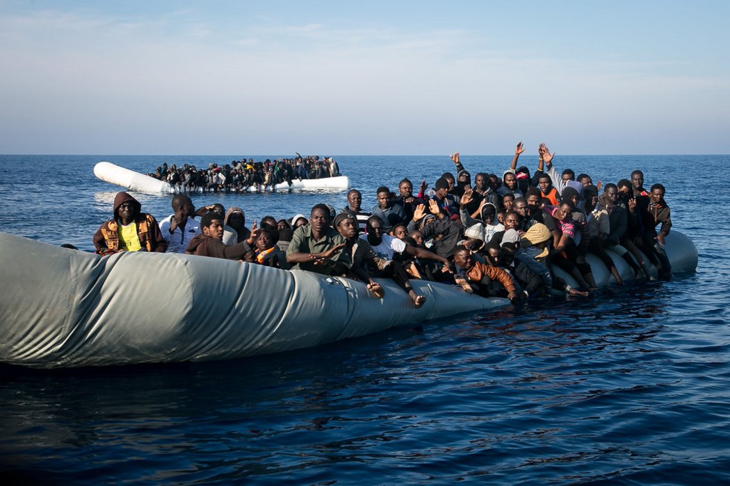 Zwei überfüllte Schlauchbote im Meer, in denen Geflüchtete Menschen sitzen. Beide am sinken.