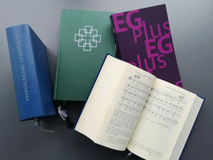 Mehrere Ausgaben von Gesangbüchern, ein Gesangbuch ist aufgeschlagen.