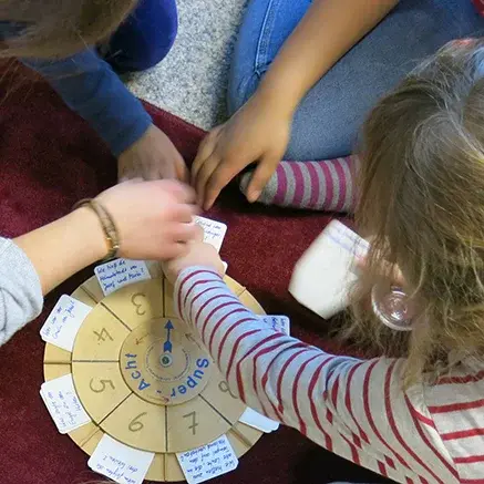 Vier Kinder sitzen und spielen gemeinsam ein Spiel.
