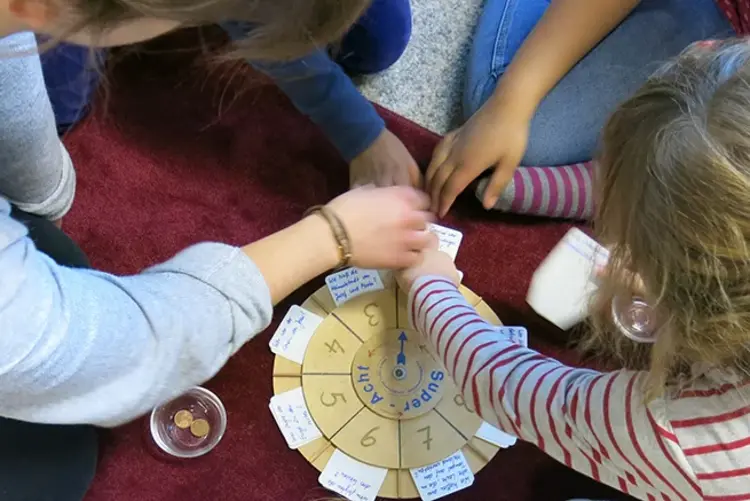 Vier Kinder sitzen und spielen gemeinsam ein Spiel.