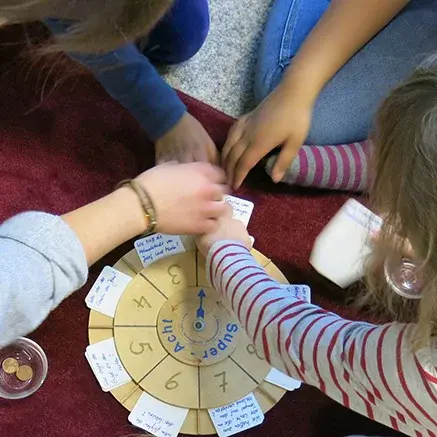 Vier Kinder sitzen und spielen gemeinsam ein Spiel.