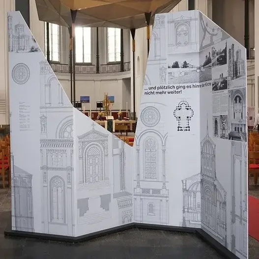 Eine großer weißer Aufsteller mit Bildern von Kirchen als Ausstellungsstück in der St. Thomas Kirche.