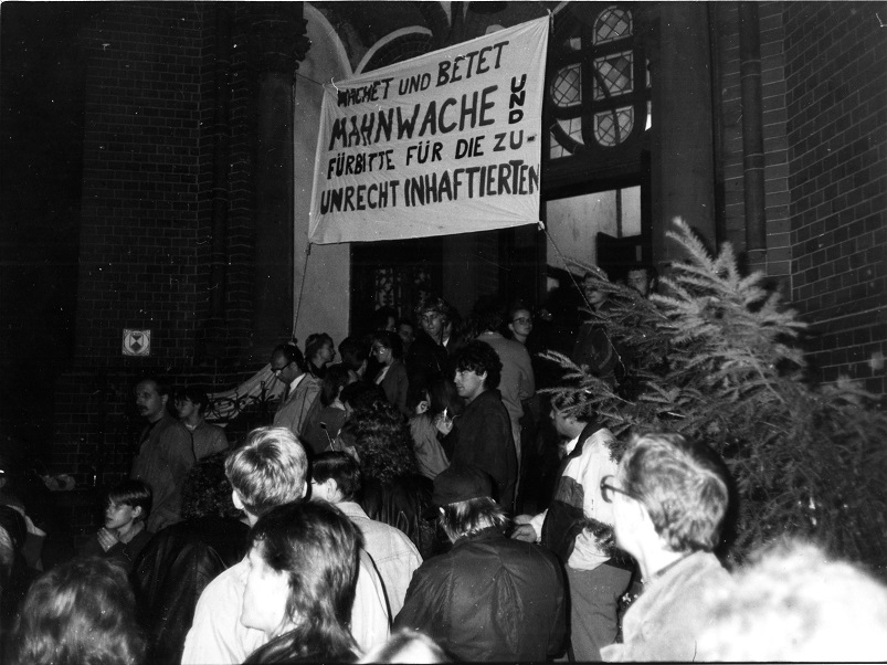 Wachet und Betet vor Gethsemane 1989. Zu sehen ist eine Mahnwache mit Plakat "Fürbitte für die zu Unrecht Inhaftierten" Foto: Frank Ebert, Quelle: Robert -Havemann-Gesellschaft, RHG_Fo_HAB_13978