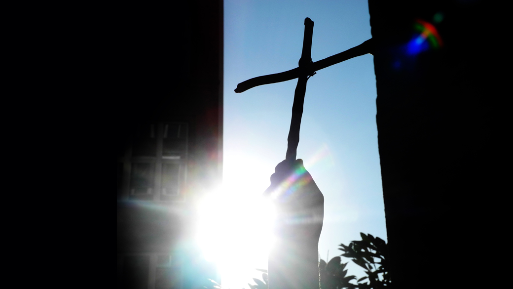 Hand hält Kreuz ins Licht